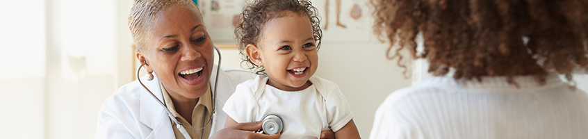 Pediatrician smiling examining a smiling toddler