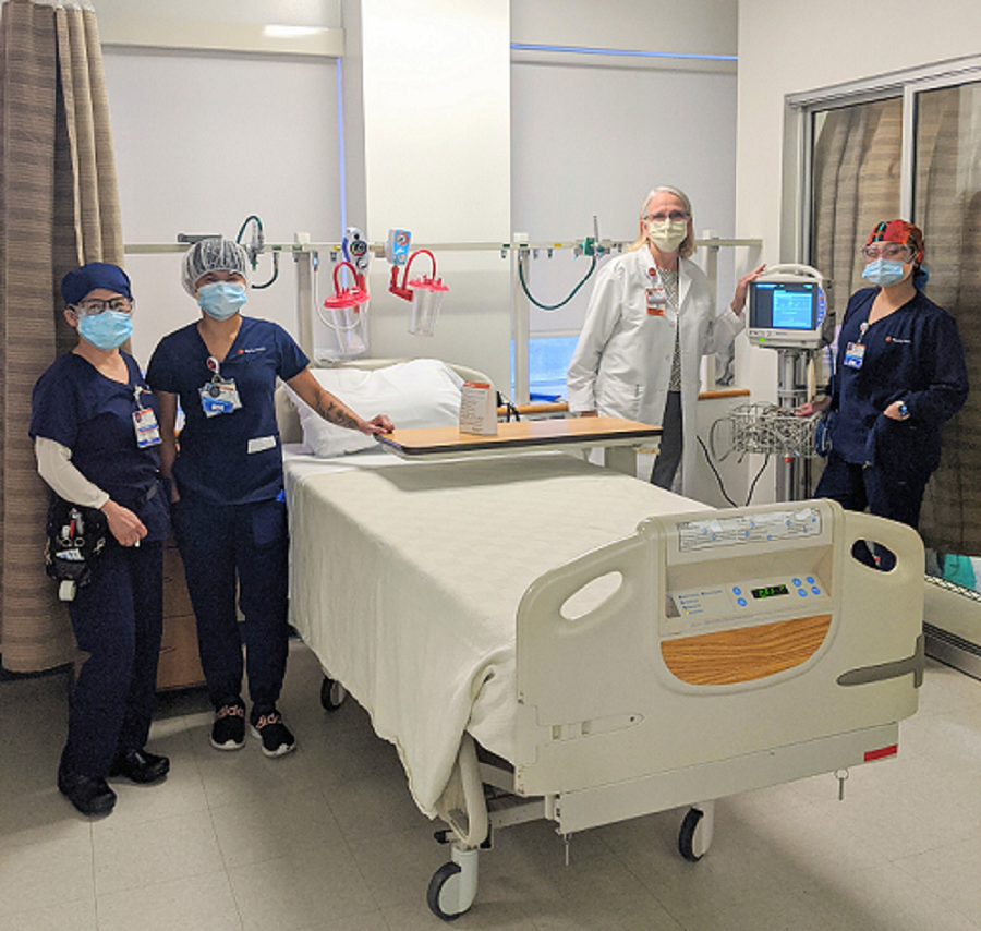 Four nurses stand around a patient bed and new DASH monitors