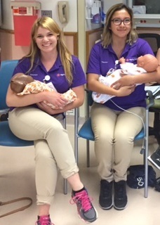 Two female volunteers hold tiny newborn babies